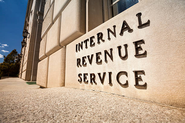 xterior view of the Internal Revenue Service (IRS) building, with the agency's name engraved on the stone facade, under a bright sky