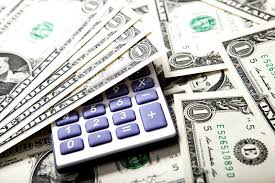 A calculator placed on top of scattered US dollar bills